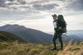 Hiking man or trail runner in mountains, inspirational landscape. Motivated hiker with backpack looking at mountain view Royalty Free Stock Photo