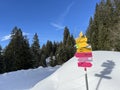 Hiking markings and orientation signs with signposts for navigating in the idyllic winter ambience of the Swiss Alps