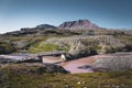 Hiking path on arctic Disko island in Greenland. River bed with bridge and colourful houses in background. Table