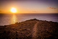 Hiking path on a rock overlooking the atlantic ocean during a colorful sunrise on the island of Gran Canaria, Canary Islands