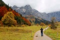 A hiking path winding thru the grassy meadow in the valley with colorful maple trees on the mountainside