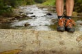 Hiking shoes legs on trunk on mountain trail.