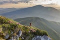 Hiking in the stoned mountains hills covered with flowering rhododendron during sunset in Carpathians