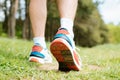 Hiking on summer day, outdoors. Man walking in nature, close-up of red sports sneakers. Dirty boot soles. Royalty Free Stock Photo