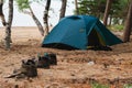 Hiking tourism adventure. Camping picnic blue tent campground in outdoor hiking forest. Touristic boots near camping