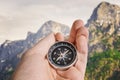 Hiking and tourism concept. Man is holding compass in hand. Mountains in background Royalty Free Stock Photo