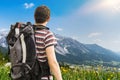 Hiking tourist with backpack from behind. Alps in background.