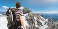 Hiking tourist with backpack from behind. Alps in background.