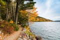 A hiking trail curves along the edge of a lake through a forest in brilliant fall colors in Acadia National Park Royalty Free Stock Photo