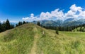 Hiking trail leading along a crest off a grassy hill with a great mountain landscape view behind in Switzerland Royalty Free Stock Photo