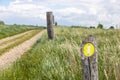Hiking trail sign, yellow plaque with a white arrow pointing the way between Dutch farmland meadows