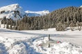 Hiking trail signpost sticks out of deep snow in mountains winter landscape on sunny day. Allgau, Bavaria, Germany.