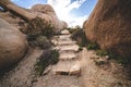 Hiking trail with steps to Arch Rock in Joshua Tree National Park, surrounded by giant boulders Royalty Free Stock Photo