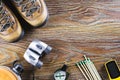 Hiking or travel equipment with boots, compass, binoculars, matches on wooden background. Active lifestyle concept