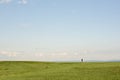 Hiking. An unknown young man walks on a green mountain on a clear summer day