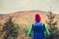 Hiking woman with backpack looking at inspirational autumn golden woods