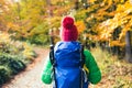 Hiking woman with backpack looking at inspirational autumn golden woods