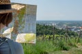 Hiking Woman with brown hair and straw hat, looking at a hiking map, wine field and Auerbach, Bensheim in the background Royalty Free Stock Photo