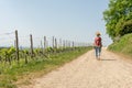 Hiking Woman with brown hair, straw hat and backpack hiking next to a wine field on a hiking trail