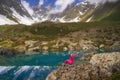 Hiking woman in red clothes sitting at beautiful turquoise lake in mountains. Royalty Free Stock Photo