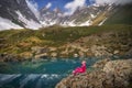 Hiking woman in red jacket sitting at beautiful lake in mountains. Royalty Free Stock Photo