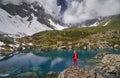 Hiking woman in red jacket stay at beautiful lake in mountains. Royalty Free Stock Photo
