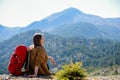 Hiking woman sit on seaside rock. Lady hiker with backpack on top of the mountain and enjoying valley view. Active Royalty Free Stock Photo