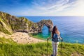 A hiking woman stands in front of the famous Durdle Door beach Royalty Free Stock Photo