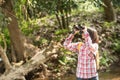 Hiking women use binoculars to travel and have a happy smile. tourist looking through binoculars considers wild birds in the Royalty Free Stock Photo