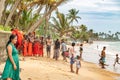 HIKKADUWA, SRI LANKA - AUGUST 27, 2019: monks in orange robes preparing for traditional bath on hikkaduwa beach