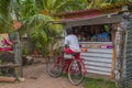 Street view in Hikkaduwa with a small shop and a man on a bicycle