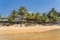 Narigama beach at Hikkaduwa with people on sunbeds and small restaurants in background