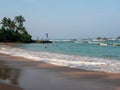 Hikkaduwa, Sri Lanka - March 4, 2022: Beautiful view of the beach in Hikkaduwa with green palm trees. People swim in the Indian Royalty Free Stock Photo