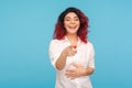 Hilarious laughter. Portrait of joyful hipster woman with fancy red hair in white shirt laughing loudly and pointing to camera