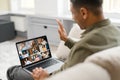 Hilarious man using laptop for video connection while staying at home. Smiling multiracial guy waving hello, greeting Royalty Free Stock Photo