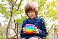 ÃÂ¡hild playing with antistress toy pop it. A joyful boy is holding and push a trendy popular finger toy. Kid trains motor skills