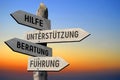 Hilfe, Unterstutzung, Beratung, Fuhrung - German/ help, support, advice, leadership - English - wooden signpost, sunset sky Royalty Free Stock Photo