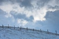 Hill with a fence covered with snow under dramatic clouds at winter, mountain Kozomor Royalty Free Stock Photo