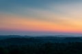 Hill layers separated with haze and vibrant glow in sky above horizon at twilight