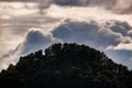 hill with pine trees under iridescent clouds Royalty Free Stock Photo