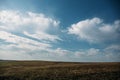 Hill and plain landscape, field of spring grass and dramatic blue sky with fluffy clouds, tranquility concept Royalty Free Stock Photo
