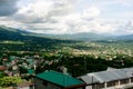 Hill station in india with buildings and grass covered hills with shadows of clouds falling on them