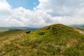 Hill summit by mountain meadow with bilberry shrubs and hills on the background in Carpathian mountains in Romania