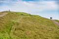 Hill walkers stroll past Worcestershire Beacon at Malvern Hills, on a summer morn