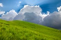 Hills covered with green grass and blue sky with white puffy clouds Royalty Free Stock Photo