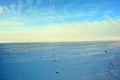 Hills covered with snow, field with sunflower cut stems, winter landscape, bright blue-golden cloudy sky Royalty Free Stock Photo