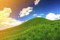 Hills with green grass and blue sky with white puffy clouds Royalty Free Stock Photo