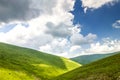 Hills with green grass and blue sky with white puffy clouds Royalty Free Stock Photo