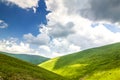 Hills with green grass and blue sky with white puffy clouds Royalty Free Stock Photo