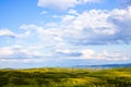 Hills with green grass and blue sky with white puffy clouds Royalty Free Stock Photo